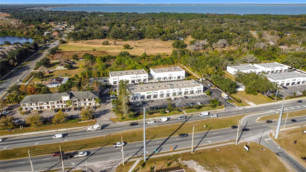 An aerial view shows a commercial plaza with parking lots situated near a highway — 1370 S NARCOOSSEE ROAD, ST CLOUD, FL