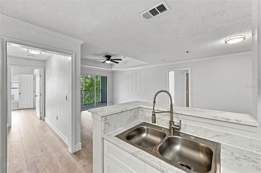 A kitchen features white cabinets, stainless steel appliances, and marble-look countertops — 18001 RICHMOND PLACE DRIVE UNIT 136, TAMPA, FL