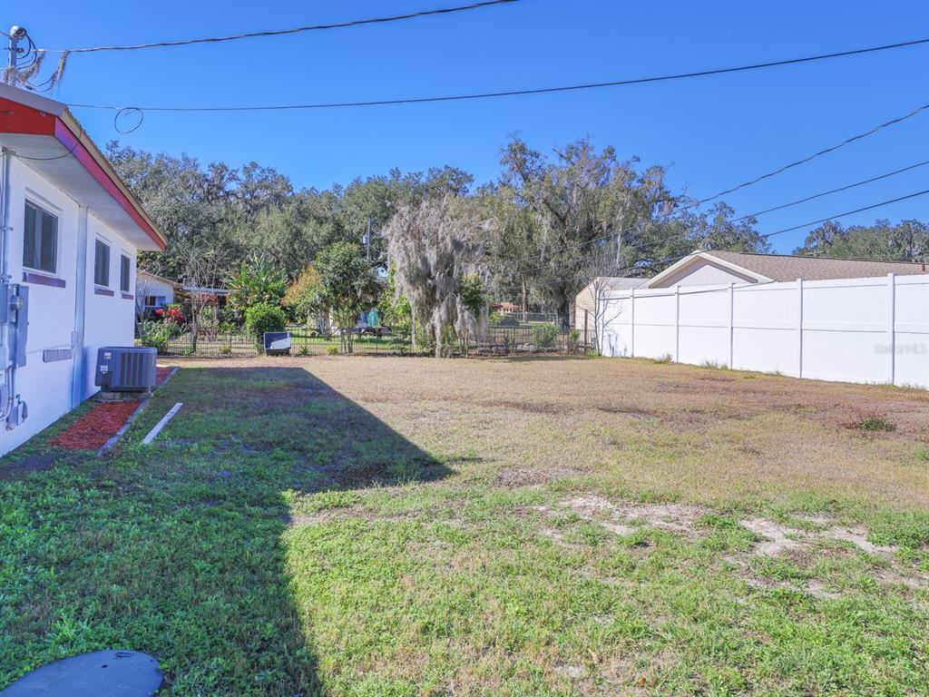 A grassy backyard features a white vinyl fence and the side of a house — 2140 E MAIN STREET, BARTOW, FL
