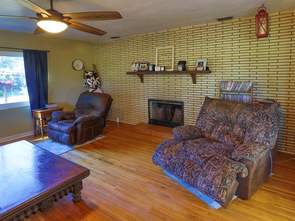 A living room features a brick fireplace, hardwood floors, a ceiling fan, and two recliners — 2140 E MAIN STREET, BARTOW, FL
