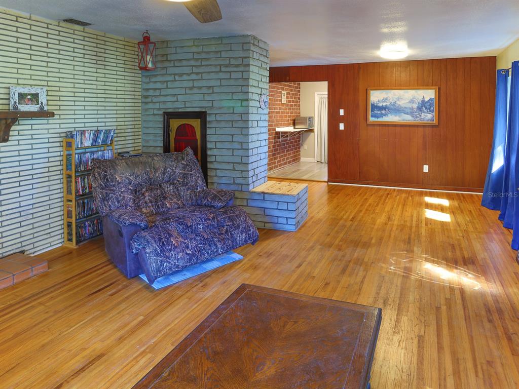 A living room features hardwood floors, a brick fireplace, wood paneling, and a recliner chair — 2140 E MAIN STREET, BARTOW, FL