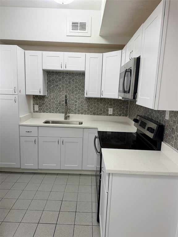 A kitchen area features a stainless steel refrigerator, tiled flooring, and a window with blinds — 1915 MORNING DRIVE, ORLANDO, FL