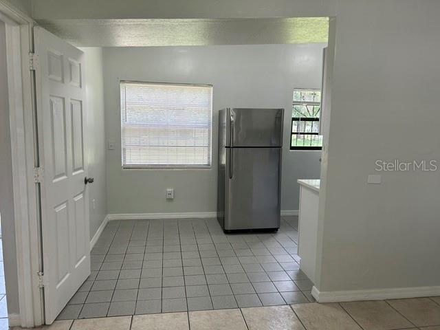 A kitchen with light gray walls, a stainless steel refrigerator, and light-colored tile flooring — 1915 MORNING DRIVE, ORLANDO, FL