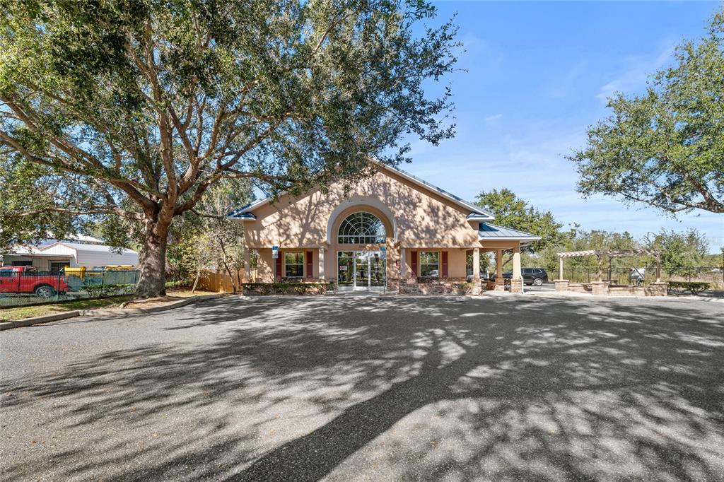 A tan commercial building with a large arched window stands behind a paved parking lot — 3300 N HIGHWAY 19A, MOUNT DORA, FL