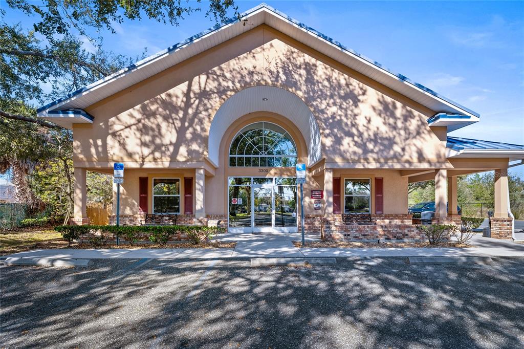 A tan commercial building with a large arched entryway and a parking lot in front — 3300 N HIGHWAY 19A, MOUNT DORA, FL
