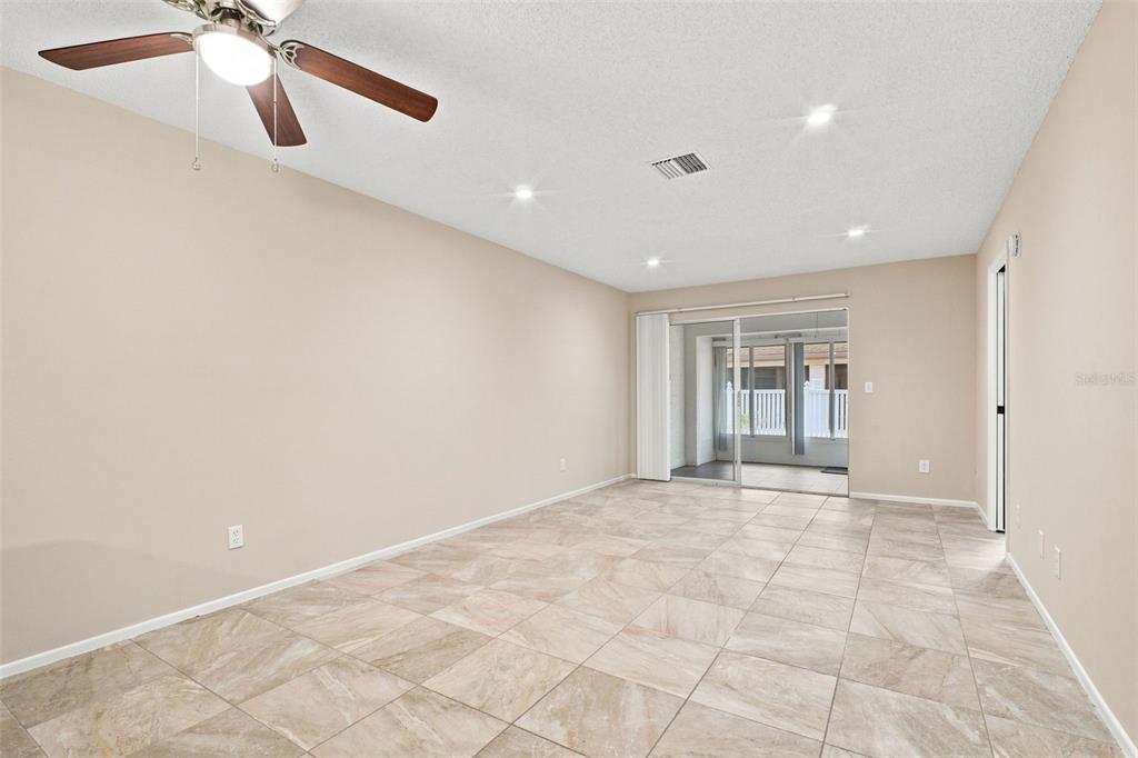 An empty room with beige walls, tile flooring, a ceiling fan, and sliding glass doors — 2460 NORTHSIDE DRIVE UNIT 1202, CLEARWATER, FL