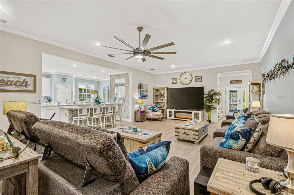A spacious living room features a large television, fireplace, ceiling fan, and open kitchen area — 6691 CAMEO DRIVE, GRANT, FL