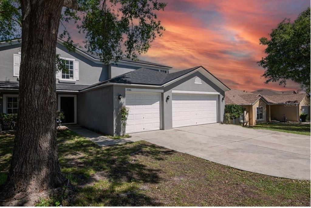 A two-story gray house with a three-car garage and a concrete driveway at sunset — 1846 WAKE FOREST AVENUE, CLERMONT, FL