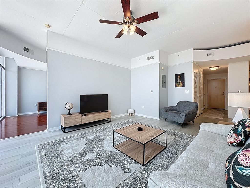 A living room features a grey sofa, a patterned area rug, and a ceiling fan — 155 S COURT AVENUE UNIT 1911, ORLANDO, FL