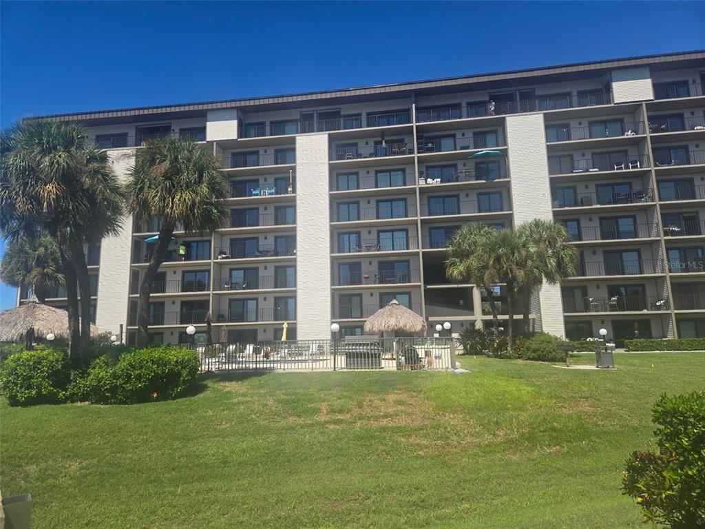A low-angle exterior view of a multi-story apartment building with a white van parked below — 650 ISLAND WAY UNIT 202, CLEARWATER BEACH, FL