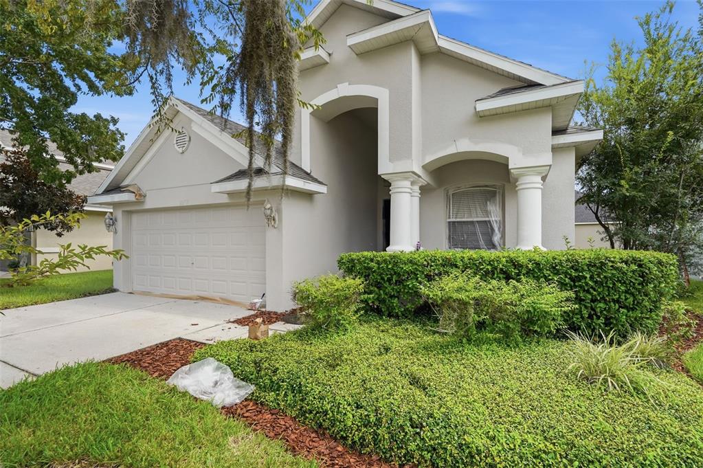 A single-story house with a beige stucco exterior, a two-car garage, and a landscaped front yard — 30718 PUMPKIN RIDGE DRIVE, WESLEY CHAPEL, FL