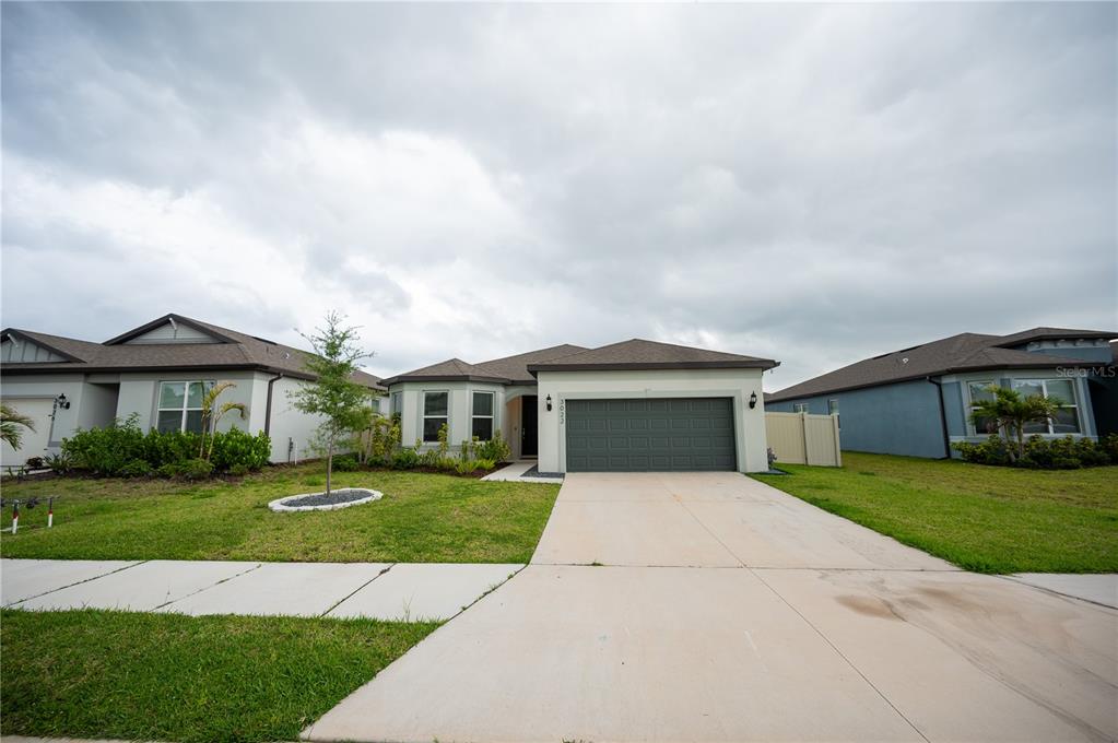 A single-story suburban house with a two-car garage, light-colored stucco, and a concrete driveway — 3022 61ST TERRACE E, ELLENTON, FL