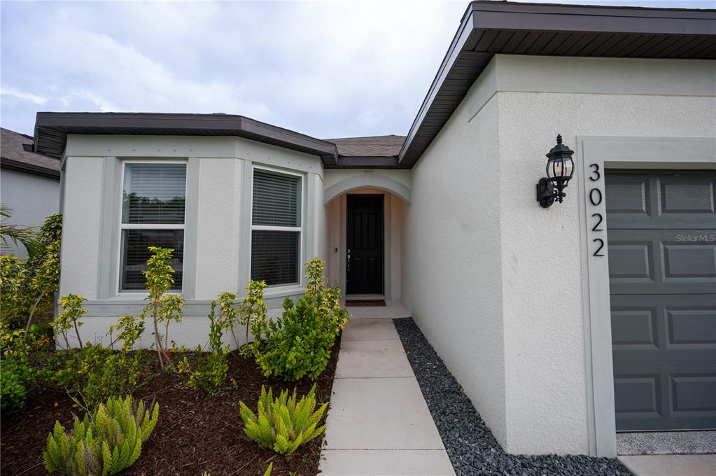 A view of a house exterior featuring a front door, a bay window, and a garage — 3022 61ST TERRACE E, ELLENTON, FL