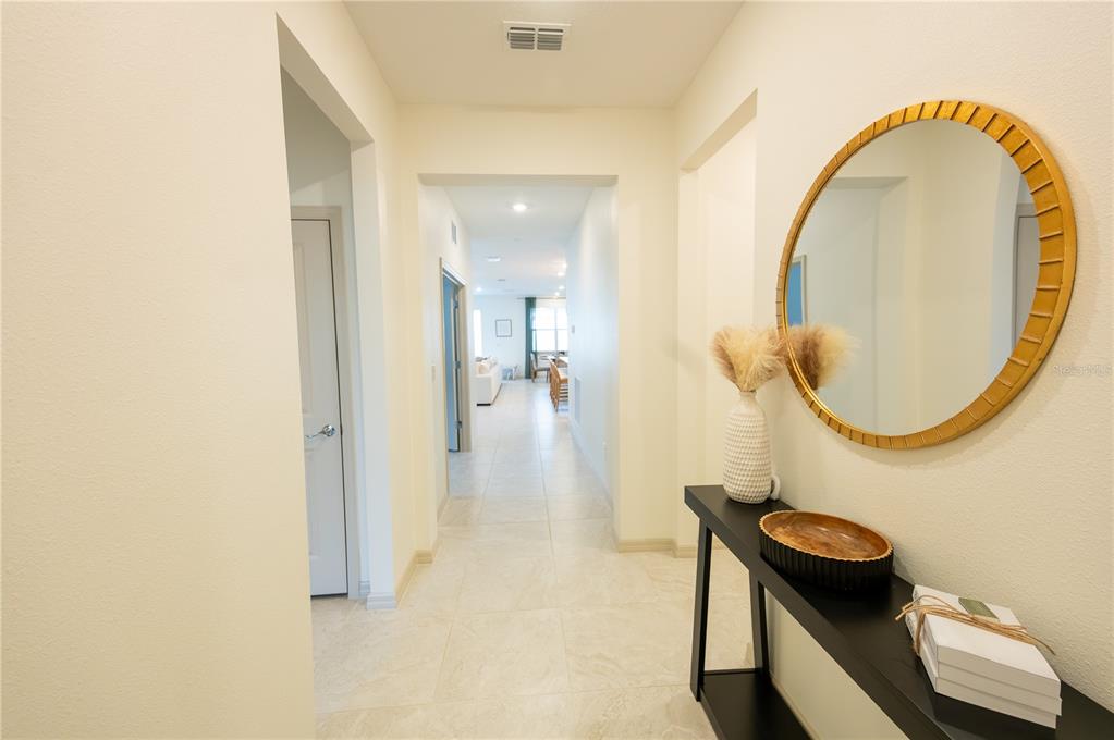 A hallway features light tile flooring, a black console table, and a round gold mirror — 3022 61ST TERRACE E, ELLENTON, FL