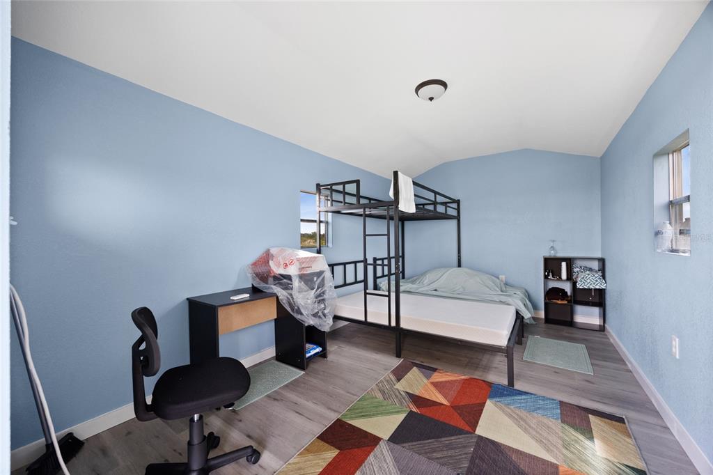 A bedroom with blue walls, wood-look flooring, a bunk bed, a desk, and a rug — 20914 NW 280TH STREET, OKEECHOBEE, FL