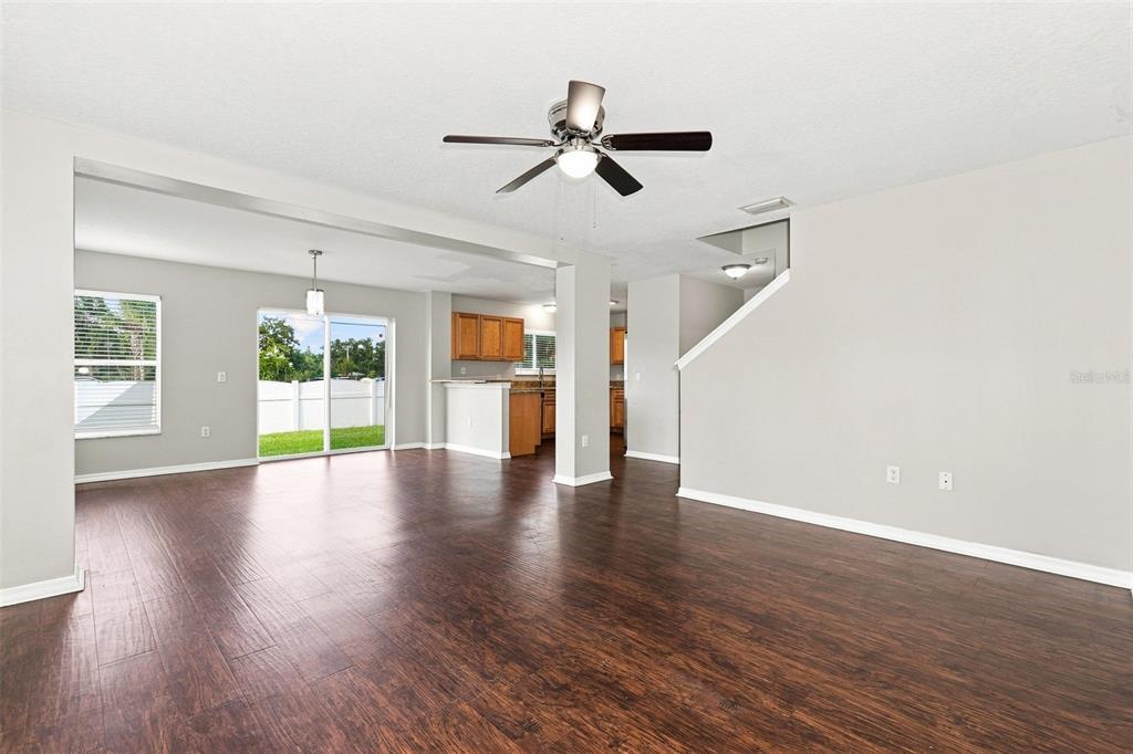 A living room with dark wood flooring, a ceiling fan, and an open kitchen beyond — 11773 MANGO CROSS COURT, SEFFNER, FL