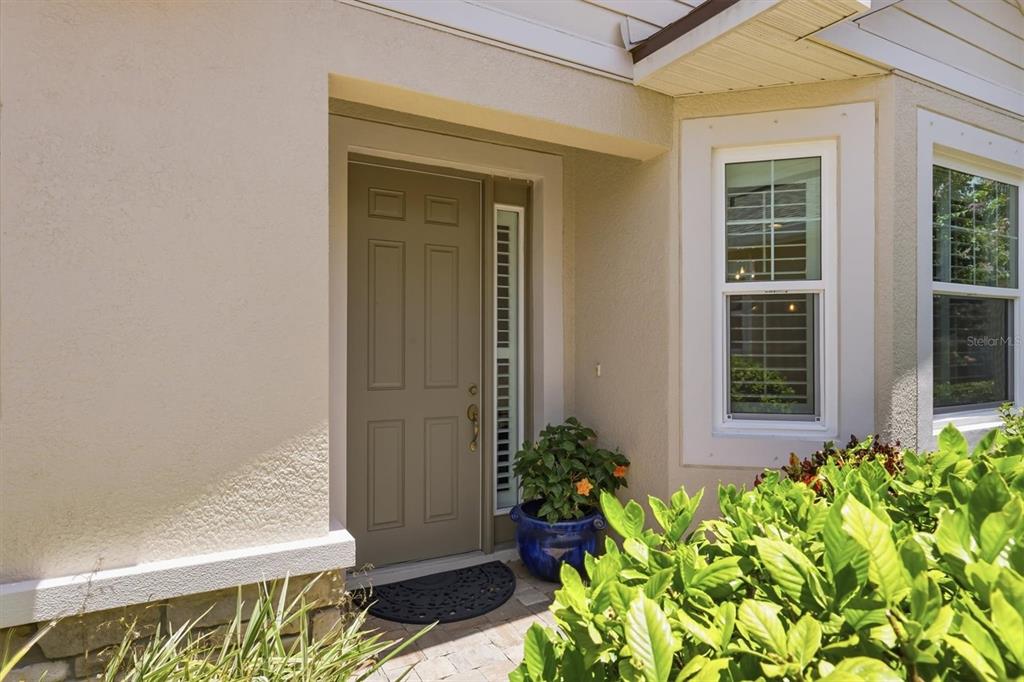 An exterior view of a home entrance with a tan door and a potted plant — 3681 DIVOT LANE, SARASOTA, FL