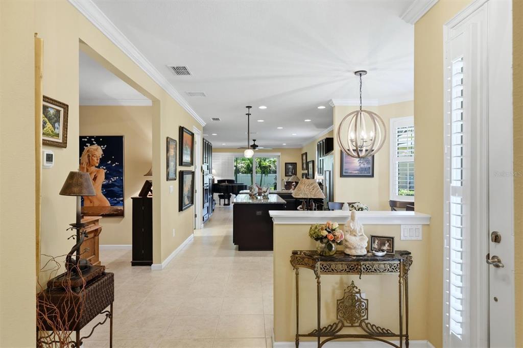 A view from an entryway looking into an open-concept kitchen and living area with tile floors — 3681 DIVOT LANE, SARASOTA, FL