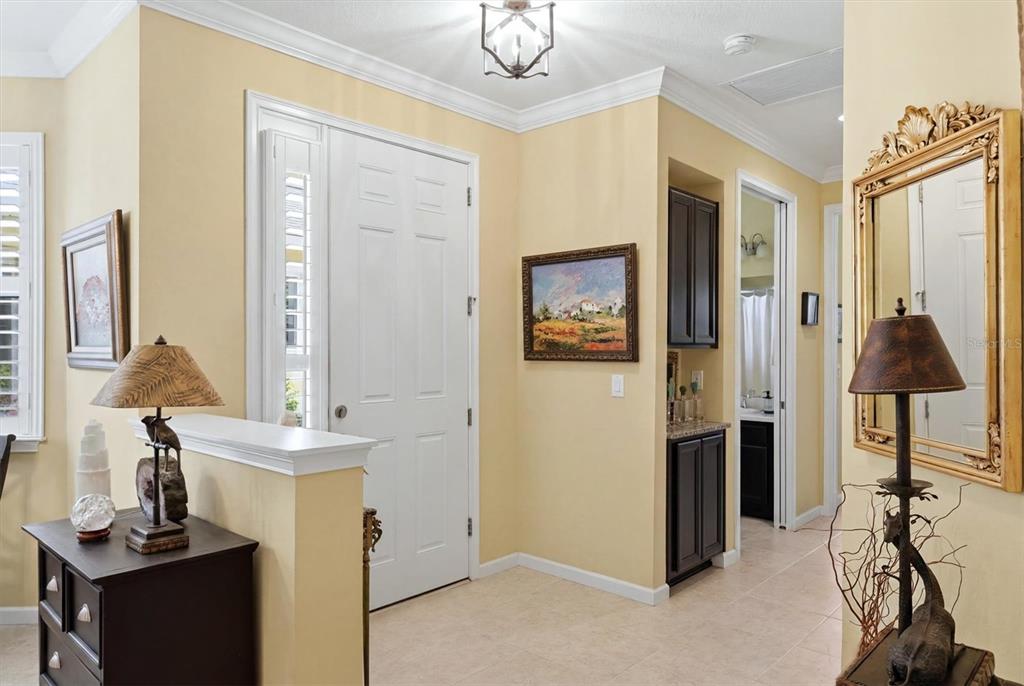 A bright entryway features a white front door, tile flooring, and a decorative wall mirror — 3681 DIVOT LANE, SARASOTA, FL