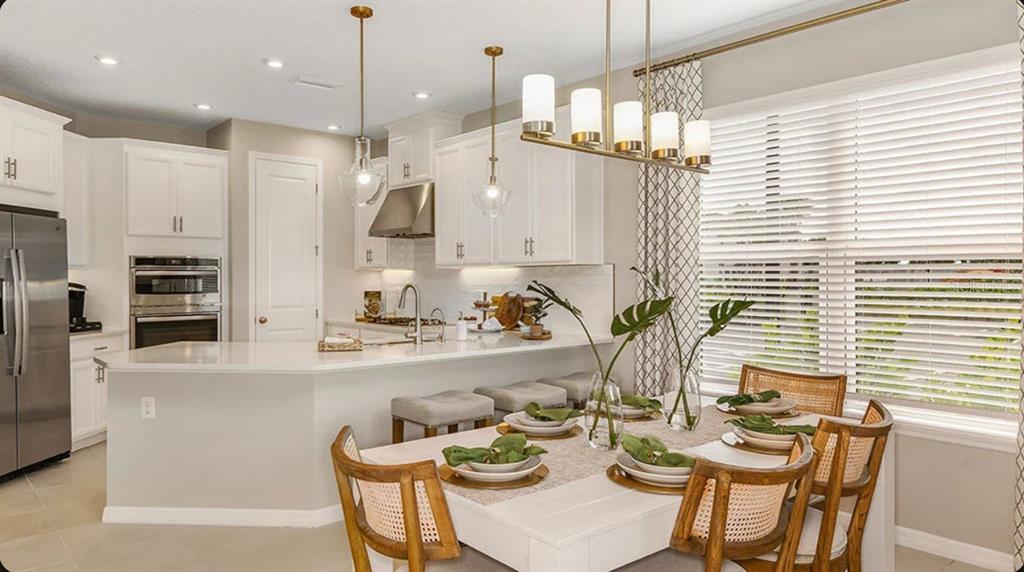 A kitchen with white cabinets and a dining area featuring a wooden table and chairs — 32477 SEA LOCH LOOP, MOUNT DORA, FL