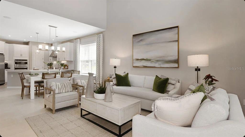 A bright, open-concept living room and dining area featuring neutral furniture and high ceilings — 32477 SEA LOCH LOOP, MOUNT DORA, FL