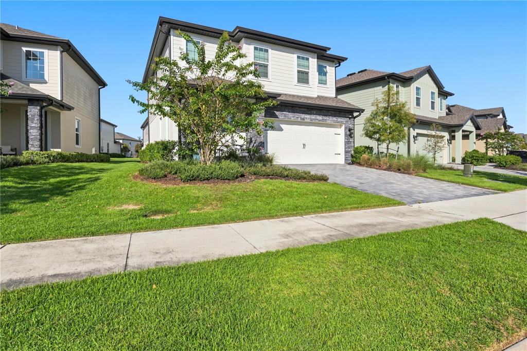 A two-story suburban house with a white garage, stone accents, and a paved driveway — 7853 SOMERSWORTH DRIVE, KISSIMMEE, FL