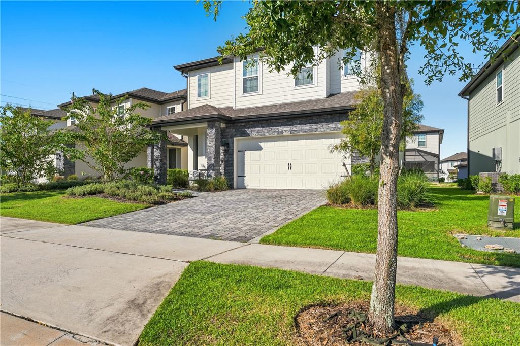 A two-story suburban house with a stone facade, white siding, and a paved driveway — 7853 SOMERSWORTH DRIVE, KISSIMMEE, FL