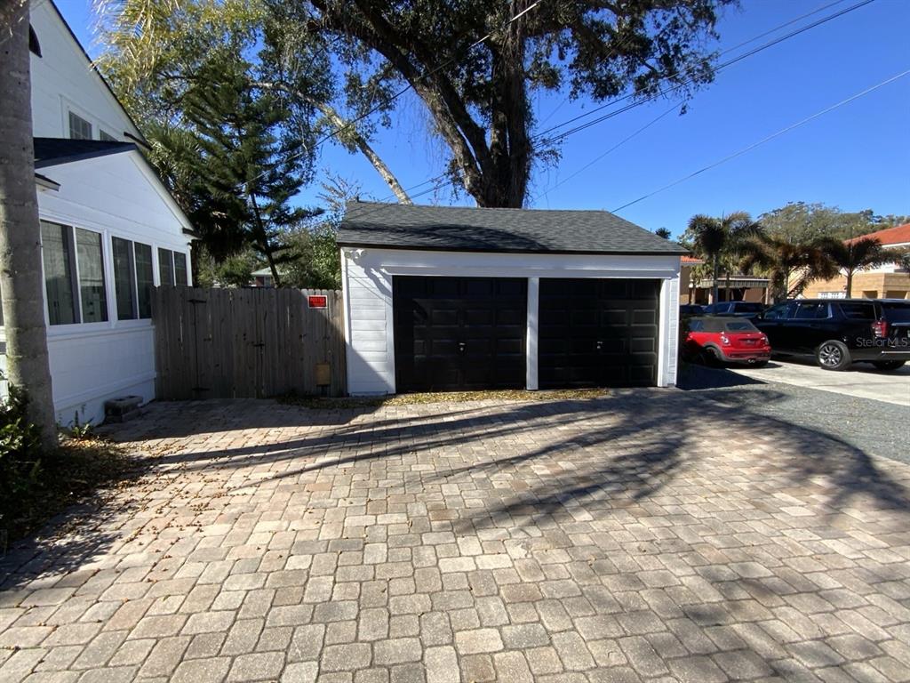 A white two-car garage with black doors sits next to a house and wooden fence — 608 HIGHLAND AVENUE, ORLANDO, FL