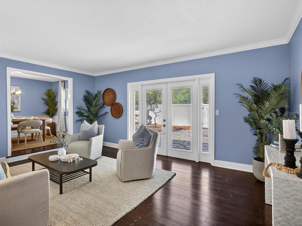 A living room with blue walls, hardwood floors, two armchairs, and glass patio doors — 333 CORNWALL ROAD, WINTER PARK, FL
