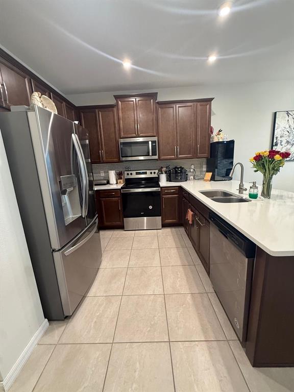 A kitchen features dark wood cabinets, stainless steel appliances, and a white quartz island countertop — 8866 HERENCIA ALY, WINDERMERE, FL