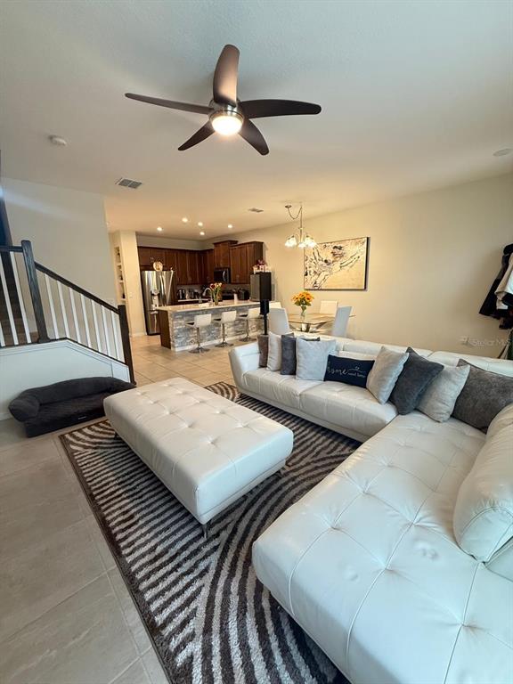An open-concept living room features a white sectional sofa, a matching ottoman, and a kitchen — 8866 HERENCIA ALY, WINDERMERE, FL