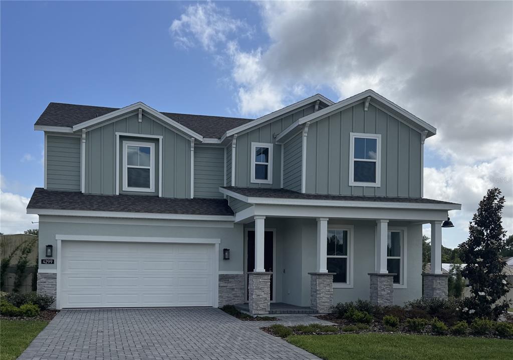 A two-story house with light green siding, a stone-accented porch, and a two-car garage — 4299 LAUREL SITE LOOP, APOPKA, FL