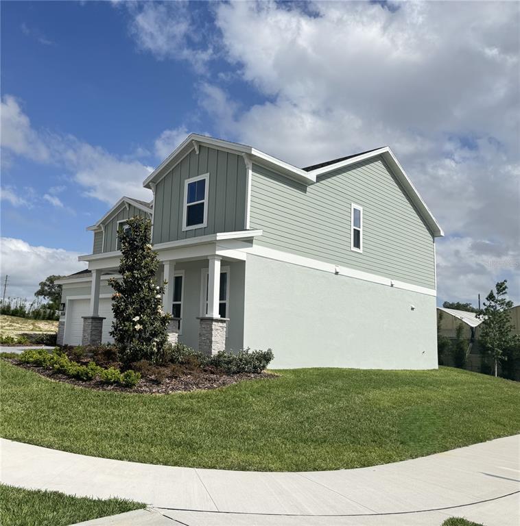 A two-story house with light green siding and a stucco base sits on a corner lot — 4299 LAUREL SITE LOOP, APOPKA, FL