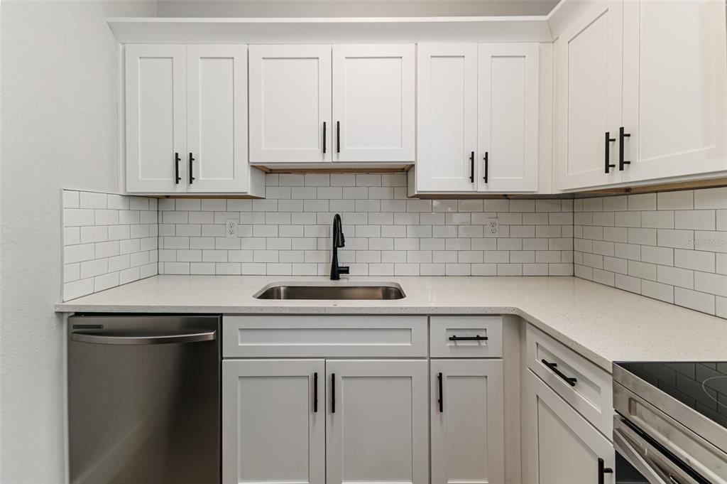 A kitchen features white cabinets, a stainless steel dishwasher, a subway tile backsplash, and countertops — 465 FORREST DRIVE, BARTOW, FL