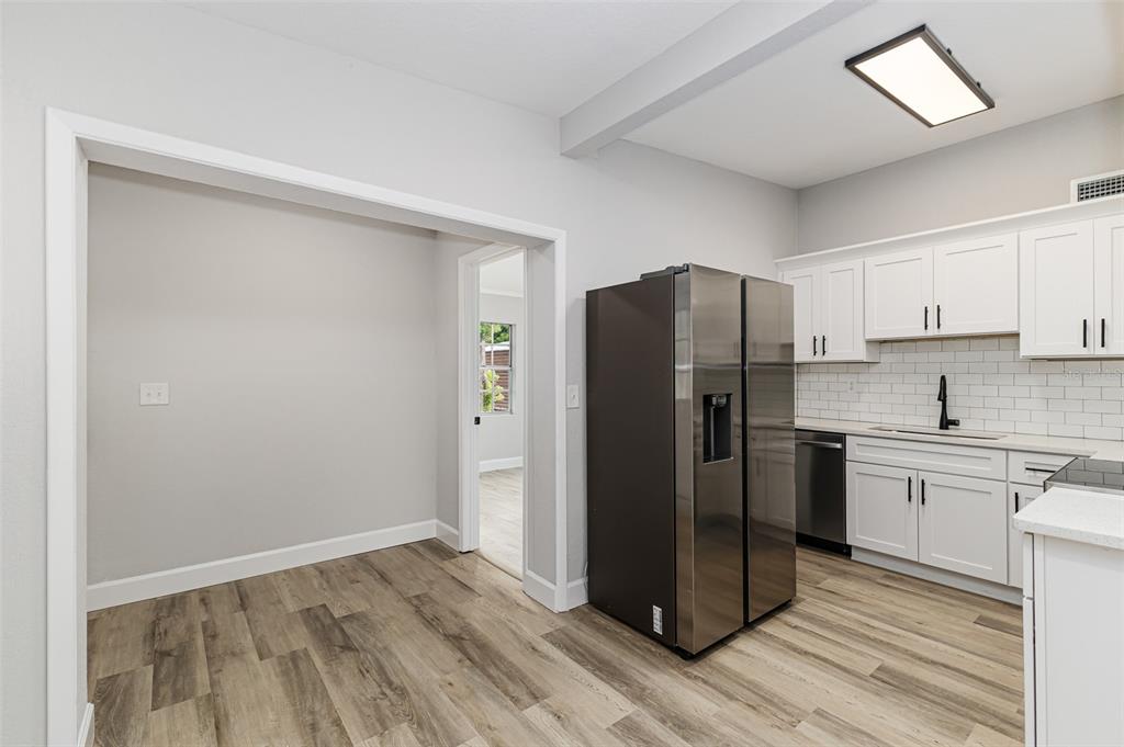 A kitchen with white cabinets, a stainless steel refrigerator, and wood-look flooring — 465 FORREST DRIVE, BARTOW, FL
