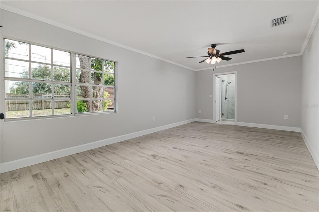 An empty bedroom with light gray walls, wood-look flooring, a ceiling fan, and a window — 465 FORREST DRIVE, BARTOW, FL
