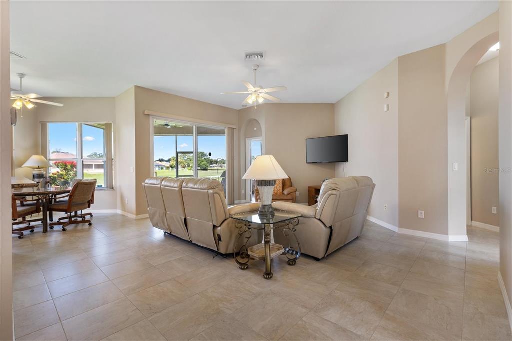 A living room features beige tile floors, two leather sofas, and a view of a backyard — 17584 SE 119TH CIRCLE, SUMMERFIELD, FL
