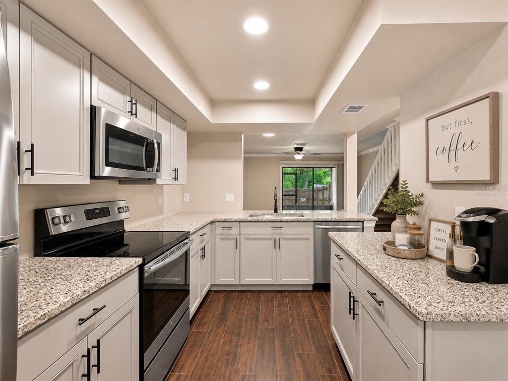 A kitchen with light gray cabinets, granite countertops, stainless steel appliances, and wood-look tile flooring — 3324 LAUREL VIEW DRIVE, BRANDON, FL