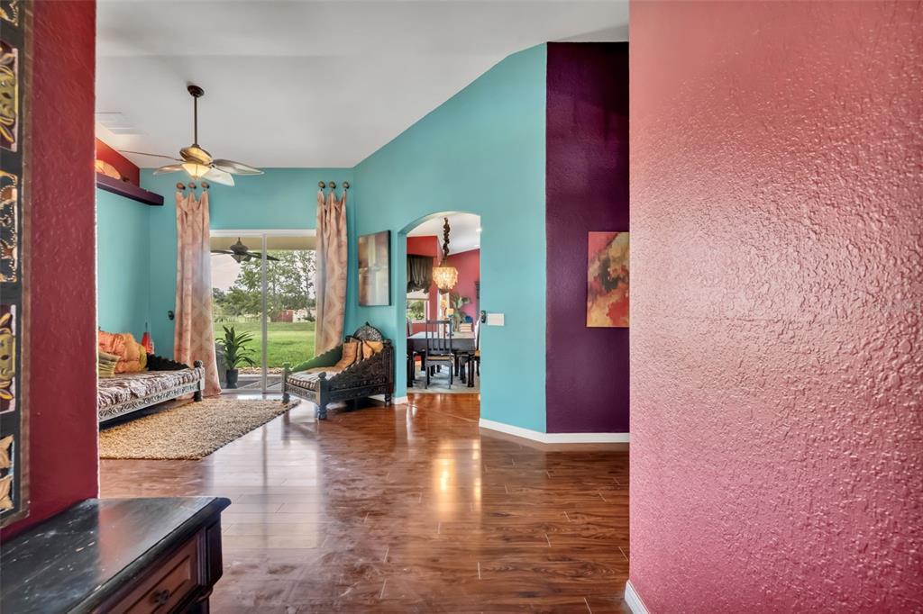A living area with turquoise and purple walls, wood-look flooring, and a view of outdoors — 4946 NE 124TH ROAD, OXFORD, FL