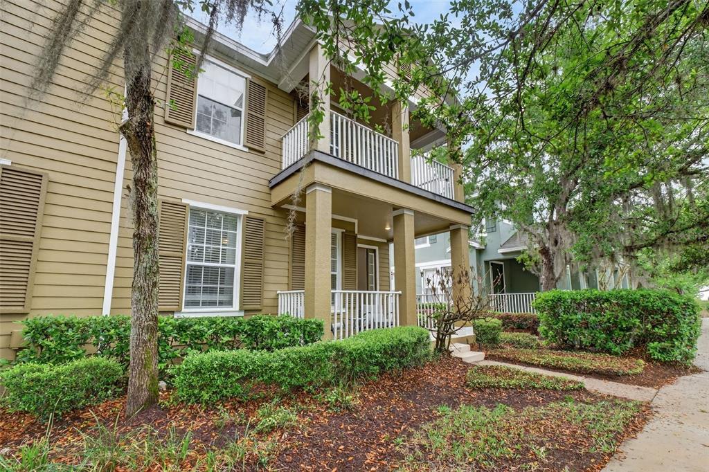 A two-story tan house features a front porch, a second-story balcony, and brown shutters — 10236 LAKE DISTRICT LANE UNIT 35C, ORLANDO, FL