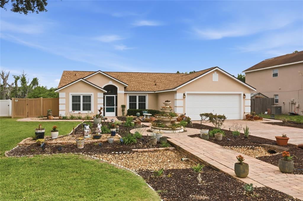 A single-story house with a beige stucco exterior, a paver walkway, and a two-car garage — 204 GREENWICH STREET, DAVENPORT, FL
