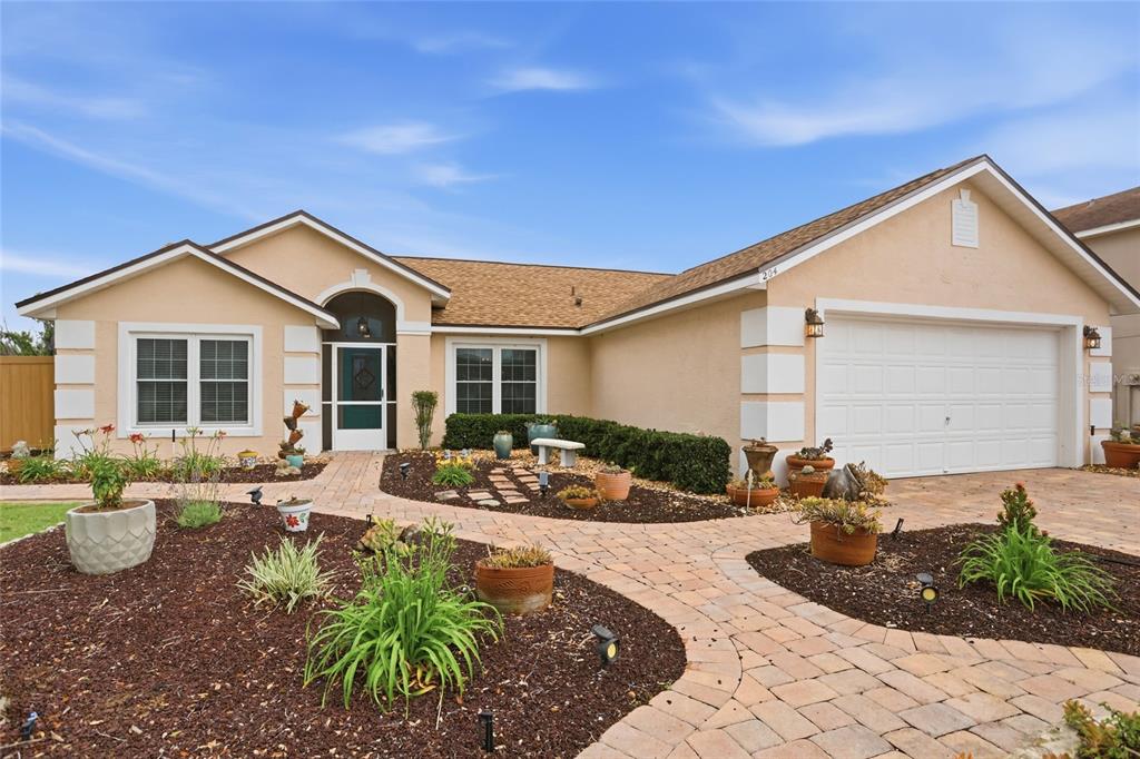 A single-story house with a tan exterior, a two-car garage, and a paved driveway — 204 GREENWICH STREET, DAVENPORT, FL
