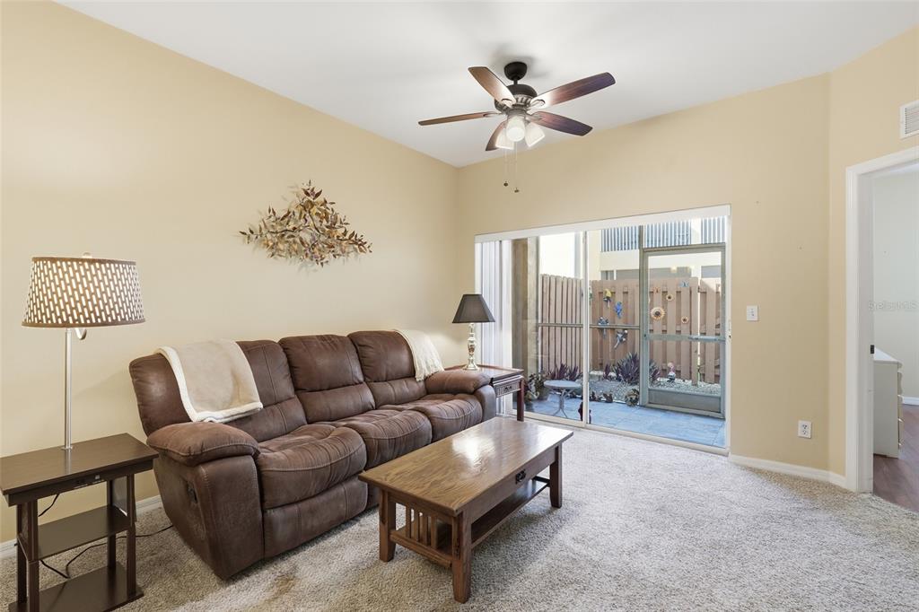 A living room features a brown sofa, a wooden coffee table, and a sliding glass door — 4259 BELLASOL CIRCLE UNIT 2013, FORT MYERS, FL