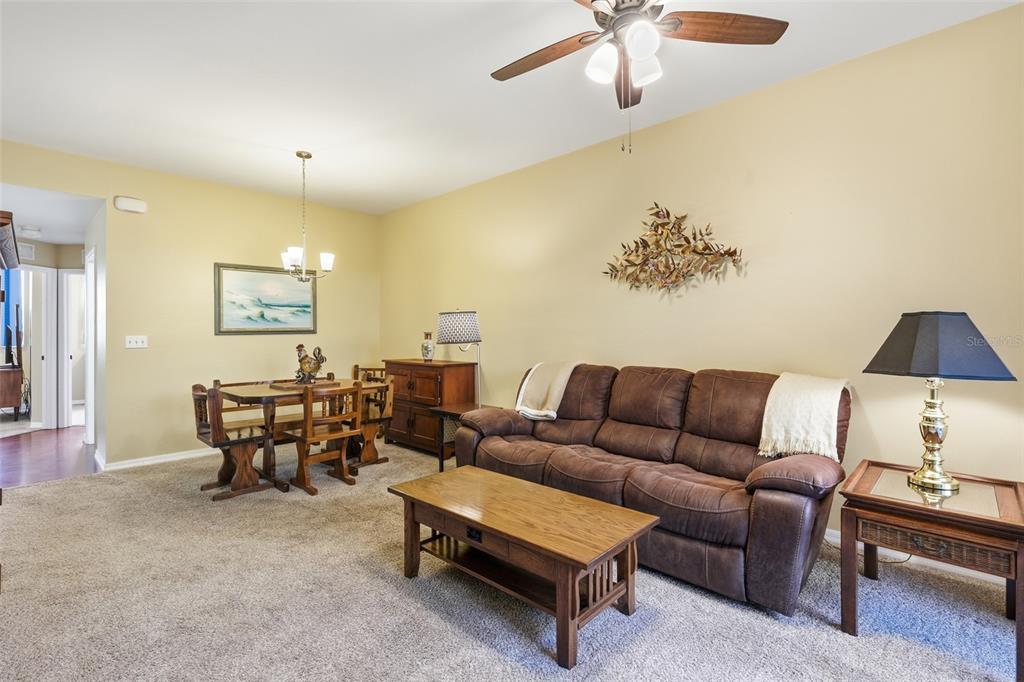 A living and dining area features a brown sofa, wooden coffee table, and carpeted floors — 4259 BELLASOL CIRCLE UNIT 2013, FORT MYERS, FL