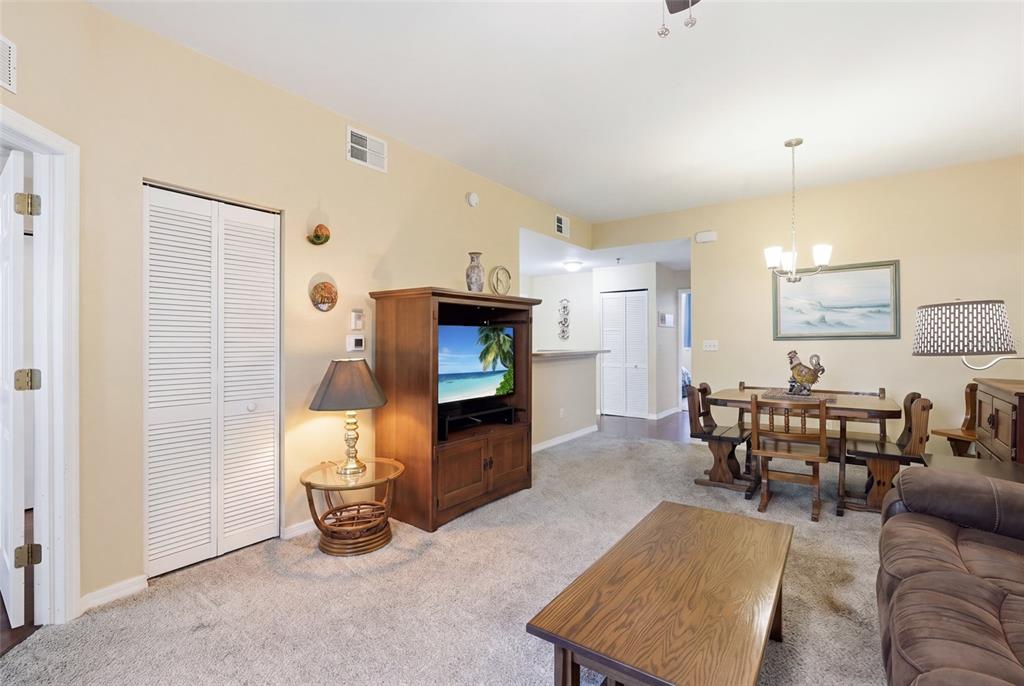 A living and dining area with carpeted floors, wooden furniture, and a television console — 4259 BELLASOL CIRCLE UNIT 2013, FORT MYERS, FL