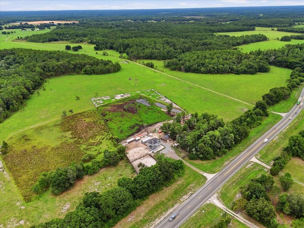 An aerial view shows a house and outbuildings on a large rural lot with pasture — 14445 COMMONWEALTH AVENUE N, POLK CITY, FL