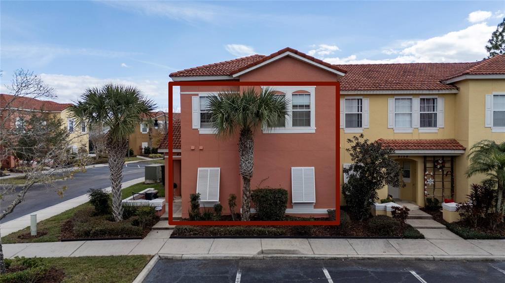 The exterior of a two-story, peach-colored townhouse features a palm tree and white shutters — 4756 ORMOND BEACH WAY, KISSIMMEE, FL