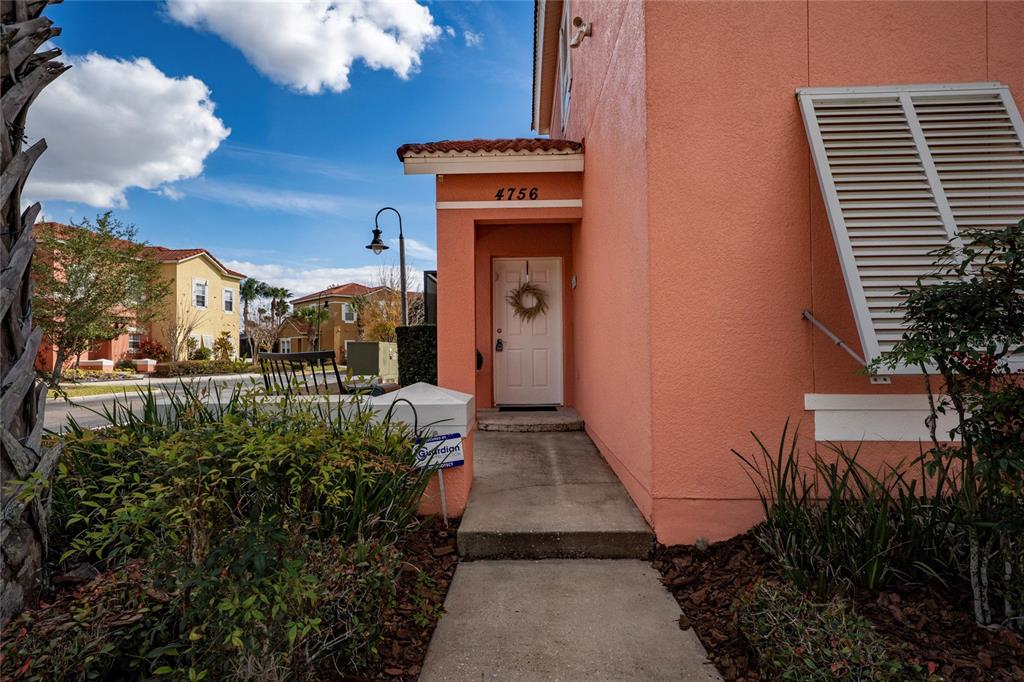 A concrete walkway leads to the front entrance of a peach-colored stucco house — 4756 ORMOND BEACH WAY, KISSIMMEE, FL