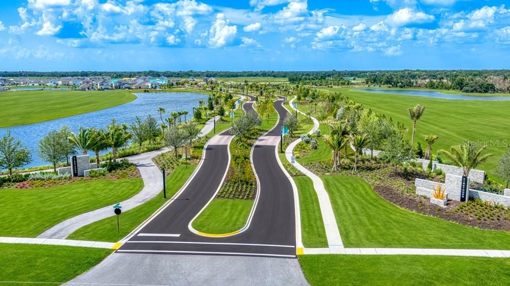 An aerial view shows a winding paved road through a landscaped community with surrounding lakes — 14226 SAWMILL STREET, PARRISH, FL
