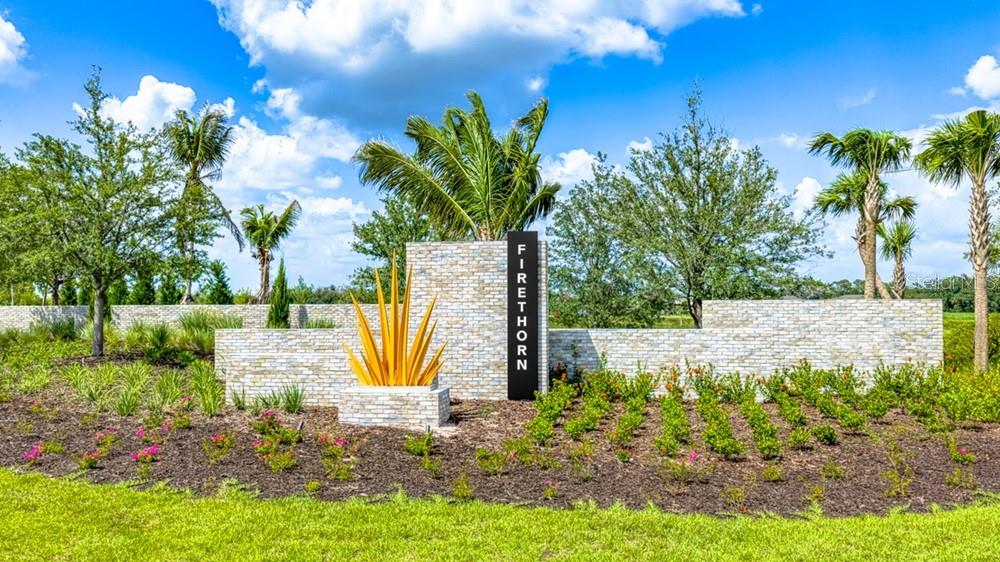 A stone wall with a Firethorn sign and a yellow metal sculpture stands outdoors — 14226 SAWMILL STREET, PARRISH, FL